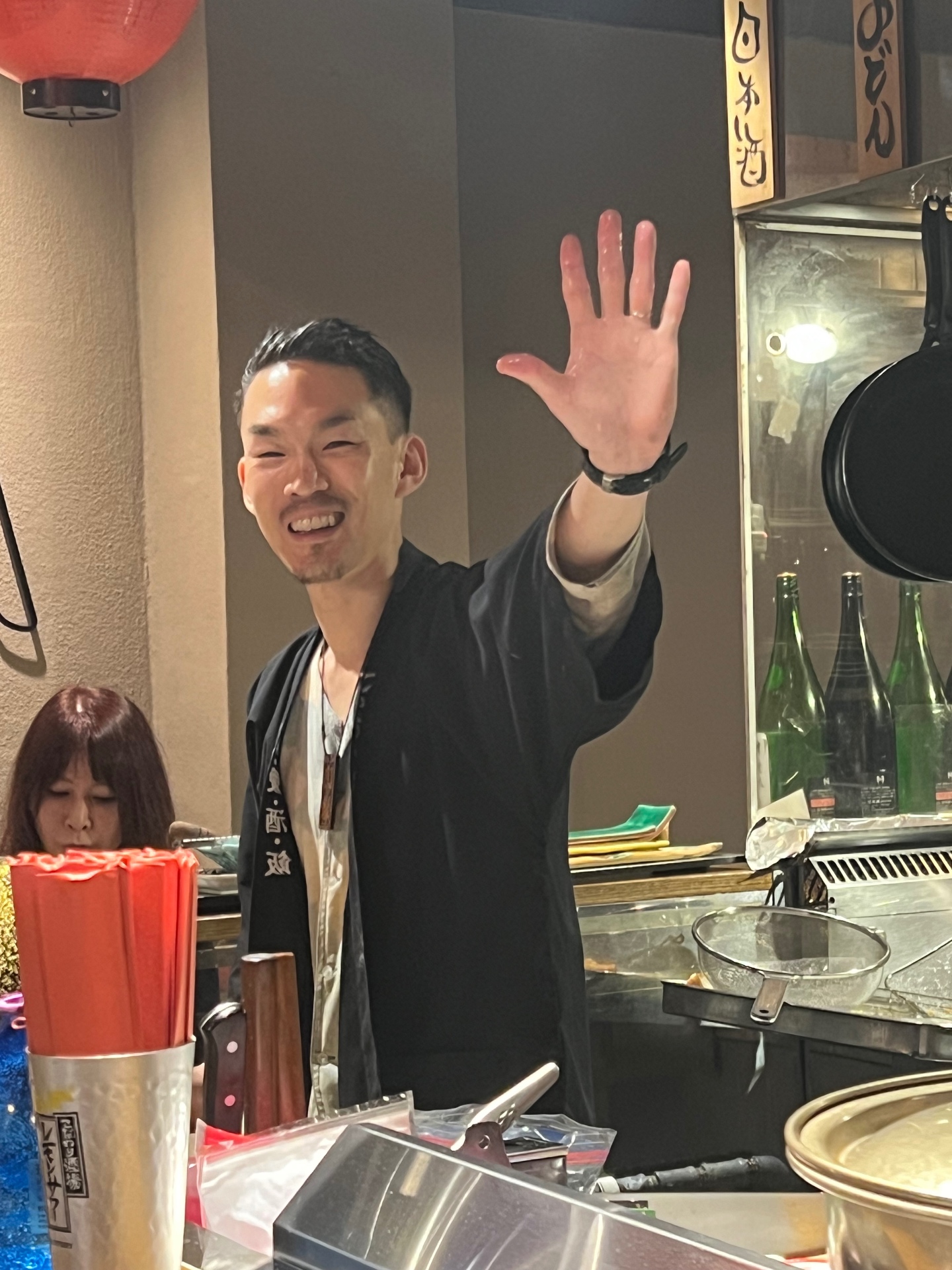 Freundlicher Koch in einer Izakaya, der in die Kamera winkt