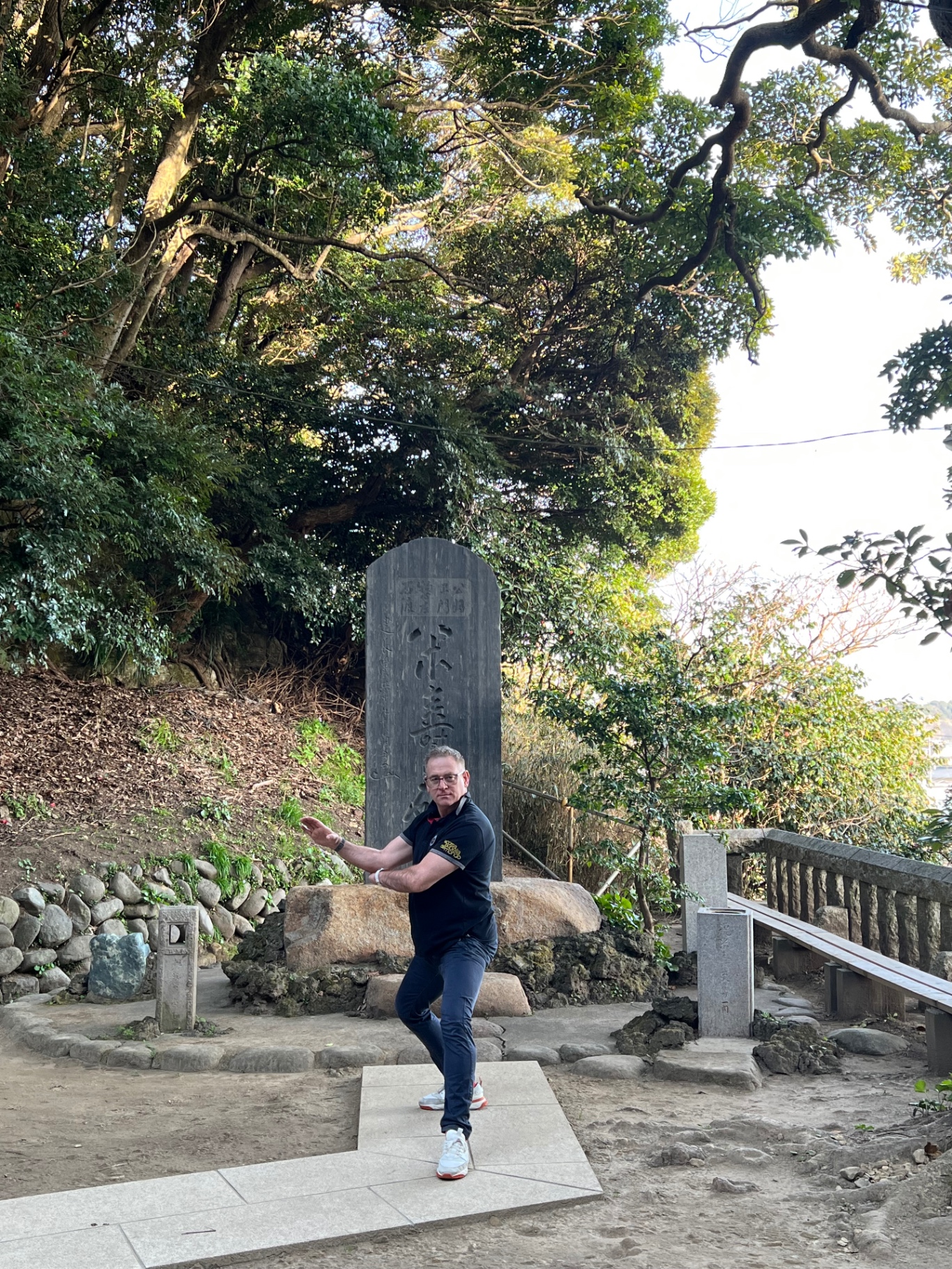 Karate-Kamae vor einer großen Steinstele mit japanischer Kalligraphie