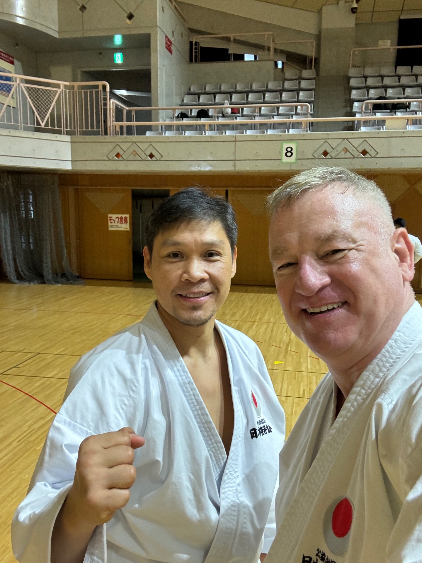 Selfie mit japanischem Karateka, der eine Faust zeigt, in der Trainingshalle