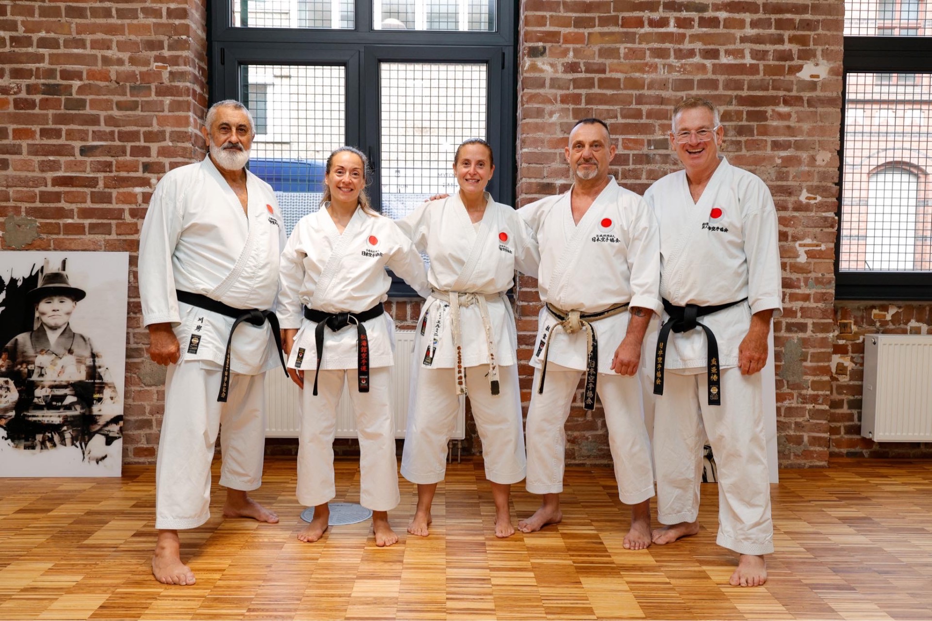 Fünf Schwarzgurte vor der Backsteinwand im Dojo