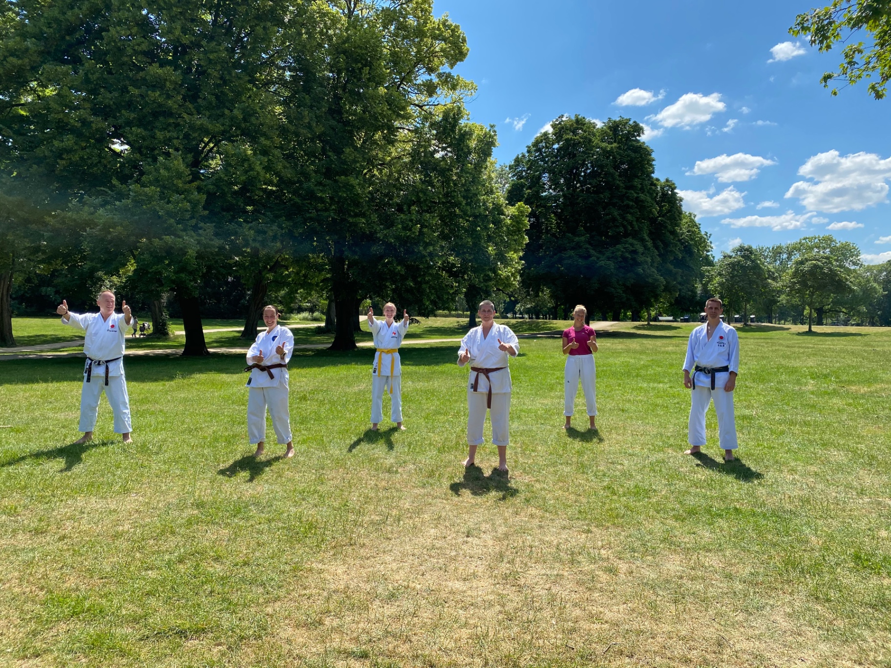 Trainingsgruppe im Park nach der Einheit mit Daumen hoch